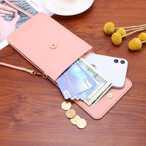 Pink minimalist crossbody phone bag with card slots and adjustable strap on a wood surface