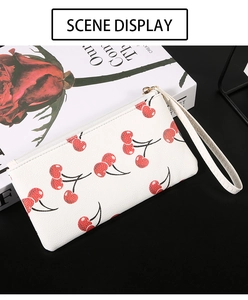Detailed view of cherry print on white lychee pattern leather wallet with wrist strap