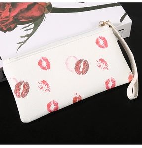 Detailed view of white pebbled leather mini purse with red lip patterns and gold zipper