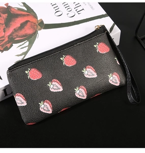 Close-up of black lychee leather purse with red strawberry print and gold zipper detail