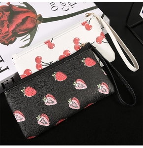 Detail of zippered wallets with cherry and strawberry prints on lychee grain leather