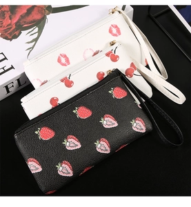 Detail of printed wristlet wallet with cherry patterns and gold zipper hardware