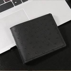 Dettaglio di un portafoglio nero in pelle goffrata struzzo su un computer portatile