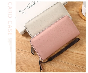 Detail of pink and beige ostrich embossed long zip wallets with fabric wrist straps