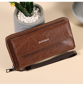 Brown leather wallet detail with lychee texture, large zipper pocket, and wrist strap