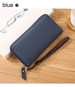 Detail of blue ostrich pattern PU leather wallet with wrist strap on wooden surface