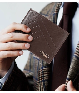 Detailed close-up of brown litchi pattern leather wallet with contrast stitching and metal logo