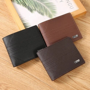 Three minimalist men's leather bifold wallets with diagonal stitching on a wooden desk