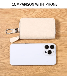 Confronto tra portachiavi in pelle PU beige e iPhone su una superficie in legno