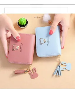 Detail of short PU leather wallets in pink and blue with bear logo and cute tassels