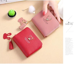 Detail of compact women's wallets in red and pink with cute bear icons and tassels
