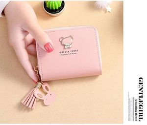 Detailed view of pink short zipper wallet with metallic bear icon and tassel charm
