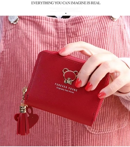 Close-up of red leather wallet featuring golden bear charm and heart tassel decoration