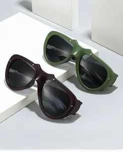 Detail of stylish wide-frame sunglasses with gold rivet accents and olive green finish