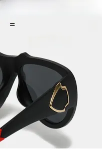 Detail showing matte black frame with golden metallic shield logo and red temple accents