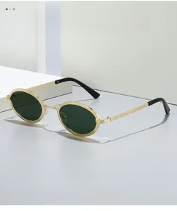 Macro detail of oval metal sunglasses showing the textured gold finish and green lens