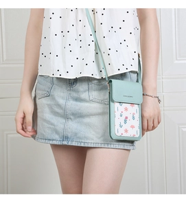 Crossbody phone bag in mint green with floral patterns worn by a model in casual style