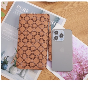 Brown long zipper wallet with geometric pattern on a wooden table with a phone