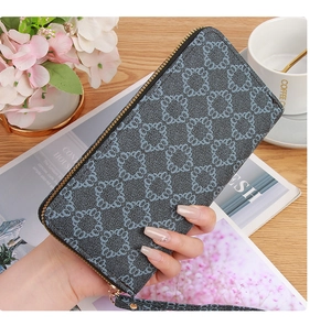 Navy blue patterned long wallet with wrist strap and gold zipper held in hand