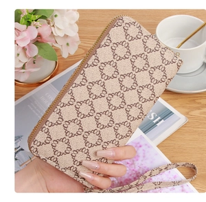 Detailed close-up of a beige patterned long wallet with a wrist strap and gold zipper