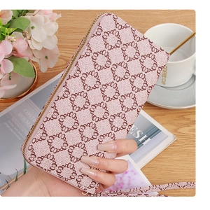 Detail of a pink floral patterned long wallet with a secure gold zipper and wrist strap