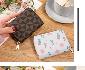 Detail of floral and geometric card holders with metal zippers on a wooden desk