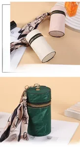 Detail of cylindrical mini pouch with gold zipper and decorative printed silk scarf