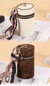 Close-up of mini cylindrical leather coin purses with gold hardware and silk ribbons