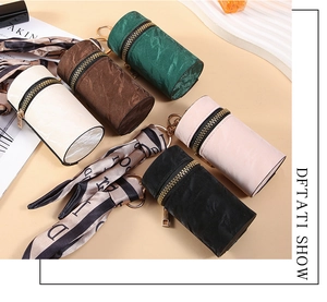 Detailed view of mini cylinder coin purses in five colors with decorative silk scarves