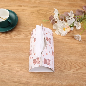 Cream leather tissue box with brown bear prints on a wooden table with a coffee cup