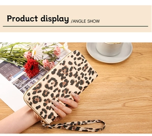 Leopard print long wallet with gold zipper and wrist strap on a wooden table