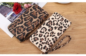 Detailed view of leopard print wristlet wallets in dark and light tones on wooden table