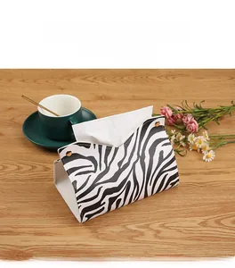 Detail of zebra pattern leather tissue box with metal rivets on a wooden table