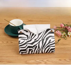 Detail of zebra pattern PU leather tissue box cover with gold buckles on wooden desk