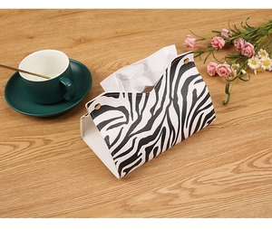 Detail view of Zebra pattern leather tissue box holder with metal buttons on wood desk