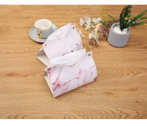 Detail of marble pattern PU leather tissue boxes with gold metal snaps on wooden desk