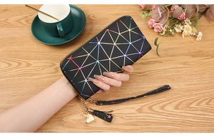 Holographic geometric clutch bag with heart pendant and tassel on a wooden desk