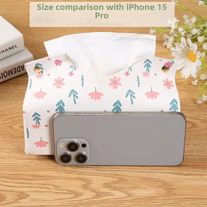 Floral PU leather tissue box cover with gold buttons next to a smartphone for scale