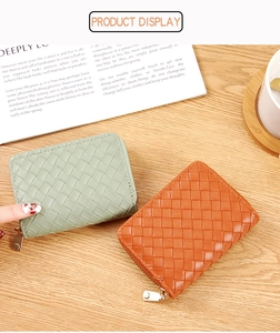 Detail of green and brown woven texture card wallets with metal zippers on wood surface