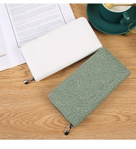 Portefeuilles à texture dentelle en blanc et vert sur table en bois décorée