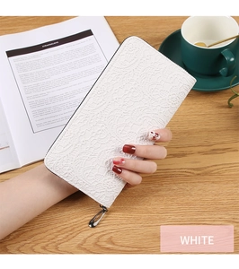Détail d'un long portefeuille blanc avec motif dentelle ajouré et fermeture éclair argentée