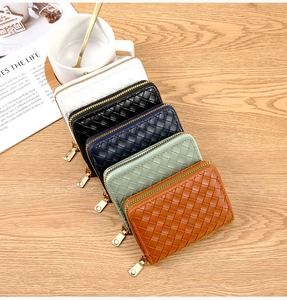 Detail of woven leather zip wallets in five colors on a wooden table setup