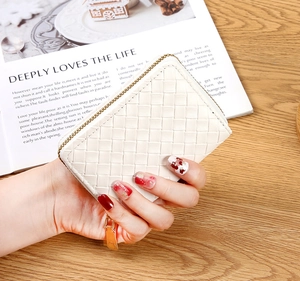 Close-up of white woven texture card holder with metal zipper on wooden background