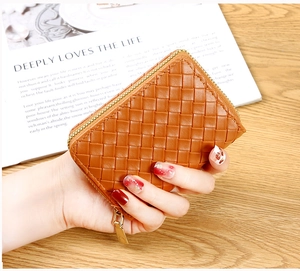 Close-up of brown woven leather card holder with gold zipper and organ style texture