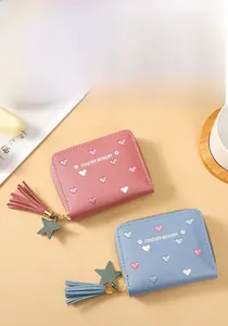 Detail of compact zip wallets with heart embroidery, fringe tassels and star charms