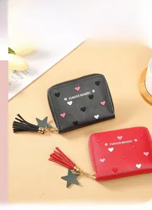 Detail of zip wallets with colorful heart patterns, leather tassels and star charms