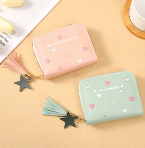 Close-up of pink and mint green wallets with heart embroidery and tassel charms