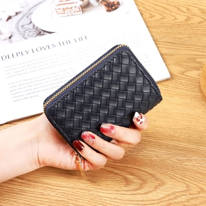Minimalist black woven leather wallet with gold zipper shown in a hand-held view