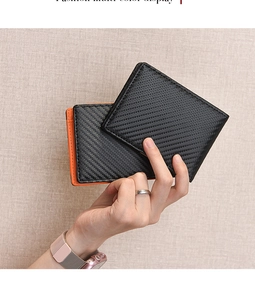 Detail of slim carbon fiber wallet showing black texture and orange side contrast