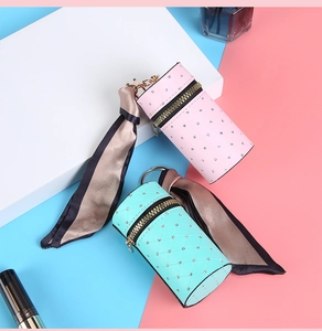 Detail of pink and green quilted mini pouch bags with gold zippers and silk scarves